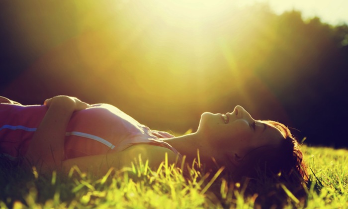 Young pretty woman lying on the grass at summer sunset