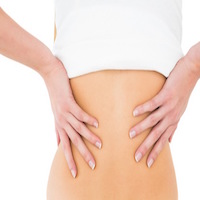 Close-up mid section of a young woman suffering from back pain over white background